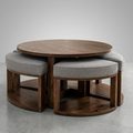 A round wooden dining table with three matching upholstered stools, photographed in a clean studio setting with a light gray background and floor.