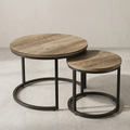 Two round nesting side tables with light brown wood grain tops and black metal circular bases, photographed in a clean studio setting.