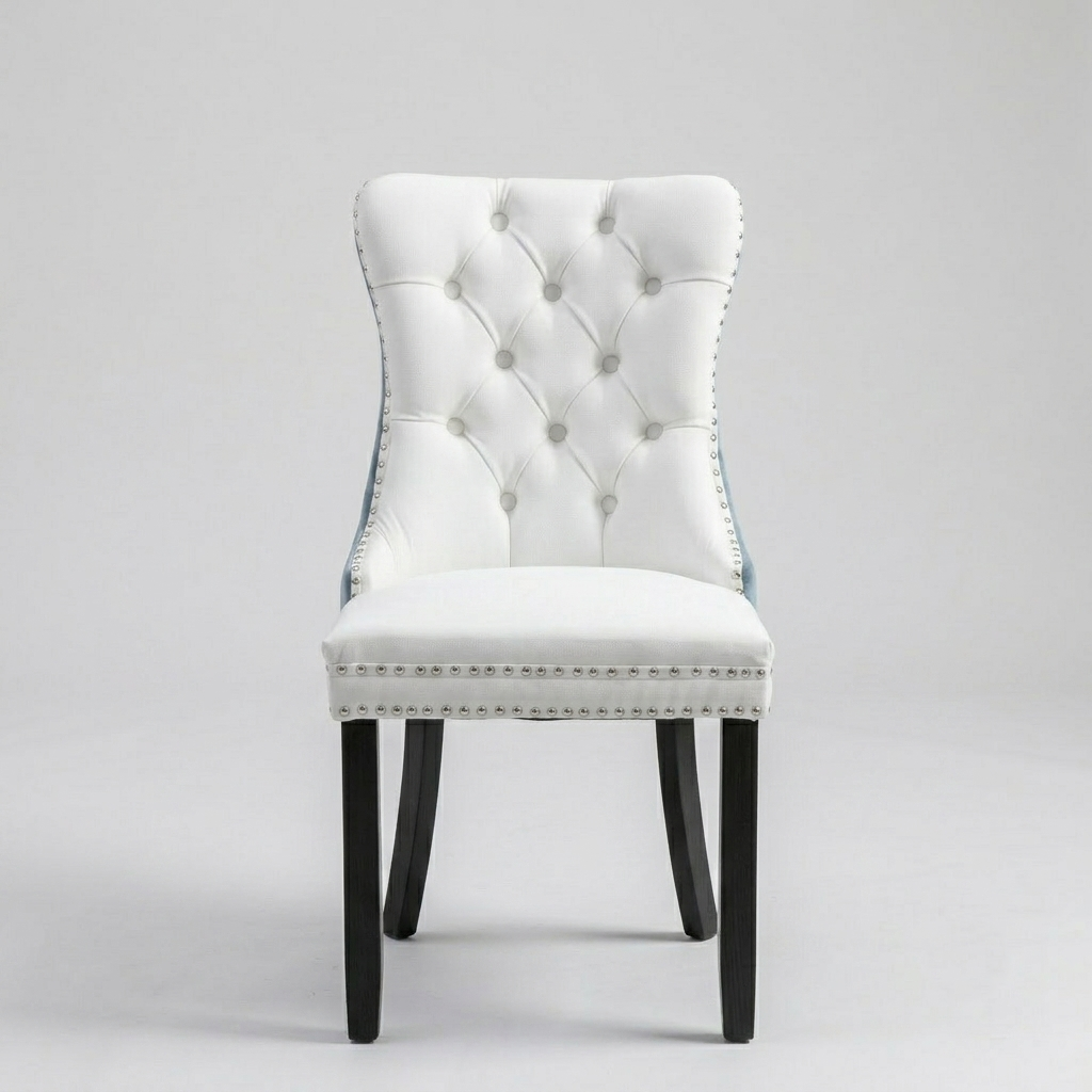 A white tufted upholstered dining chair with black wooden legs and silver nailhead trim, photographed against a neutral light gray studio background.