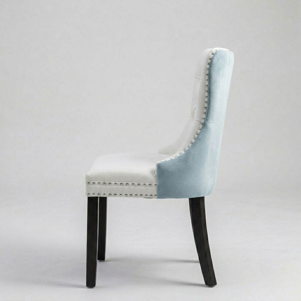 A high-back dining chair upholstered in light blue velvet with a white seat cushion and silver nailhead trim, supported by dark wooden legs, shown against a neutral light gray background.