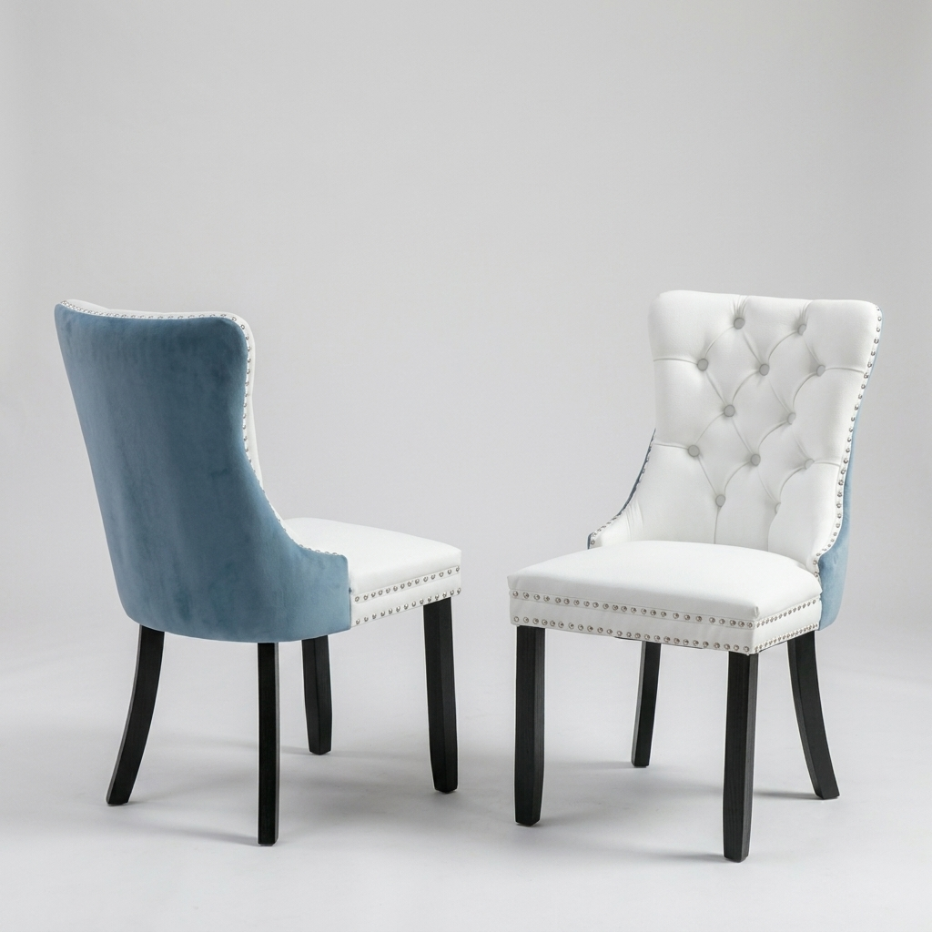 Two upholstered dining chairs shown on a light gray studio background. One chair is shown from the back in dusty blue velvet with a white seat and black legs; the other is shown from the front in white upholstery with tufted detailing, silver nailhead trim, and black legs.