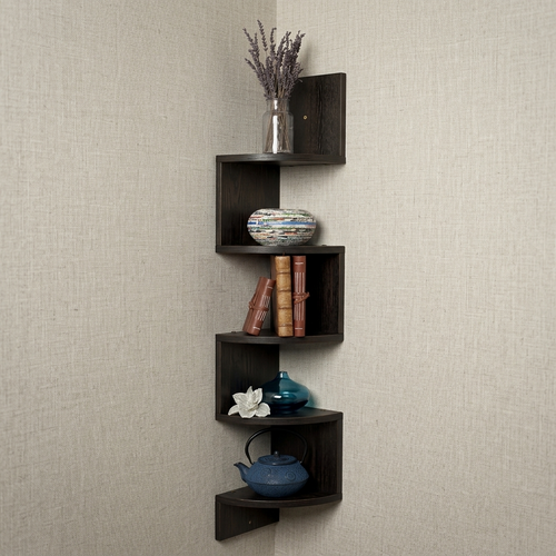 A dark brown corner wall shelf set with five nested L-shaped tiers, styled with a silver vase of dried lavender, a patterned ceramic bowl, books, a blue vase, a white flower, and a blue teapot, mounted on a textured beige wall.