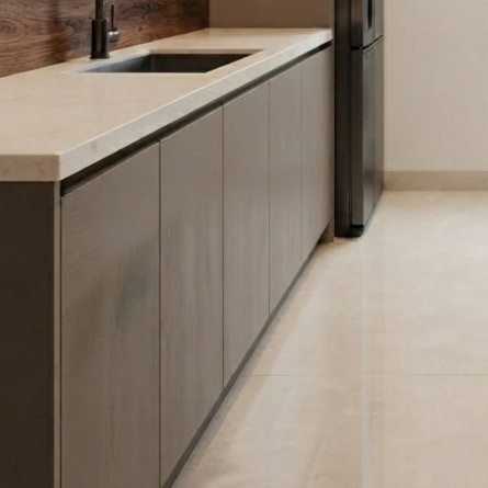 Modern kitchen cabinetry with matte taupe-gray wood grain doors, a light beige stone countertop, a black sink, and a dark refrigerator in a minimalist interior.