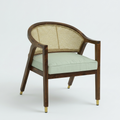 A modern accent chair with a dark brown wooden frame, a woven cane backrest, a light sage green seat cushion, and brass-colored metal caps on the legs, shown against a plain light gray background.