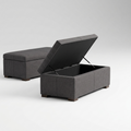 Two gray upholstered storage ottomans on a light gray studio background, with one ottoman open to show the lift-up lid and storage compartment.