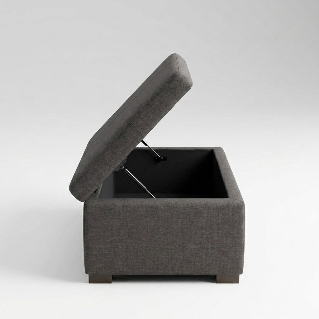 A dark gray upholstered storage ottoman with its lid propped open on a metal gas lift, shown against a light gray studio background.