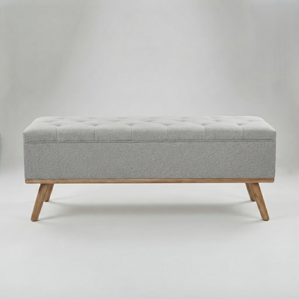 A rectangular storage bench with a tufted light gray upholstered top and wooden legs, shown against a neutral light gray studio background.