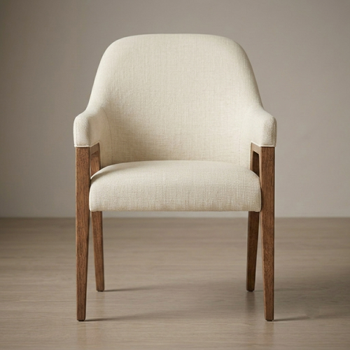 An upholstered accent chair with a cream-colored textured fabric seat and backrest, supported by a medium brown wooden frame with tapered legs, set against a neutral beige wall and light wood floor.